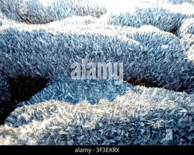 A detailed closeup shot captures the intricate patterns of delicate hoar frost crystals on a textured surface Stock Photo