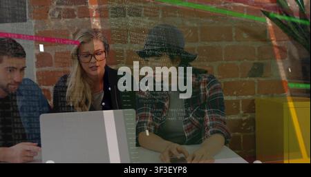 Woman in fedora reaching keyboard, showing code overlay while team debugging laptop for tech review Stock Photo