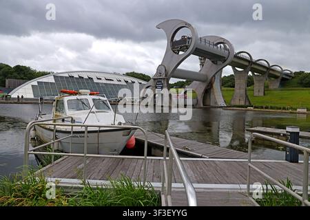 Moored boat and marina pontoon beneath the Falkirk Wheel, the world’s only rotating boat lift linking two Scottish canals. FK1 4RS Stock Photo