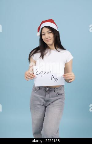 Young woman wearing santa hat holding white sign board studio Stock Photo