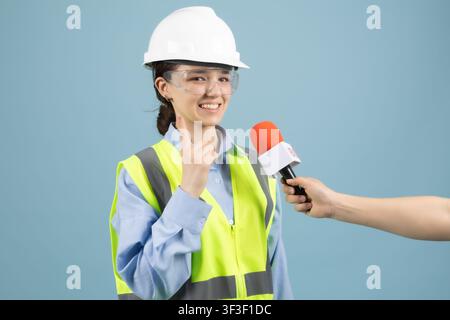 Female worker answering reporter microphone interview questions studio Stock Photo