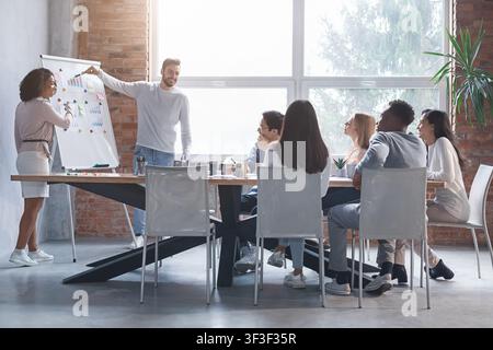 Young man and woman making marketing report to colleagues Stock Photo