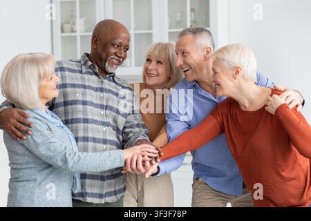 Happy Multiracial Group Of Friends Smiling And Holding Hands In Home Setting, Togetherness Concept Stock Photo