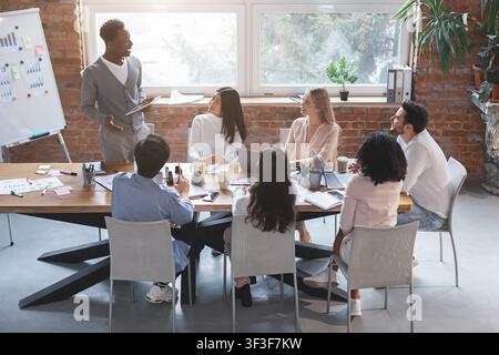 Enthusiastic black guy sharing creative ideas with team Stock Photo