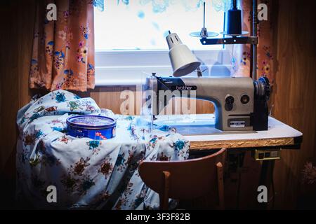 Vintage Industrial Sewing Machine with Floral Fabric in Craft Room Stock Photo
