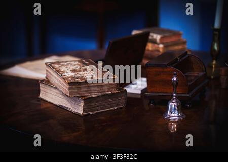 Antique Leather-Bound Books and Silver Desk Bell on Wooden Table Stock Photo
