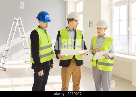 Engineers and inspectors reviewing blueprints interior renovation site meeting Stock Photo