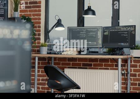 Multiple computer monitors display parsing code and programming language compiling in an empty software development agency office. Stock Photo
