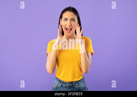 Lady holding hand near mouth, screaming at camera Stock Photo