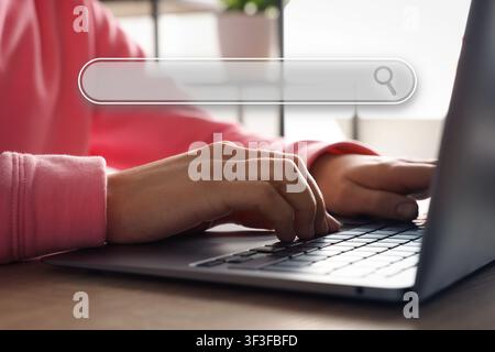 Search bar and woman using laptop at table. Closeup view Stock Photo