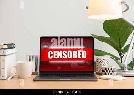 Censored content. Laptop displaying notification on desk Stock Photo