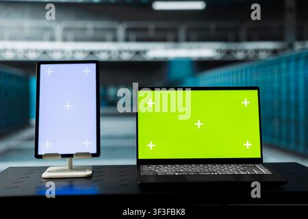 Green screen laptop and tablet overseeing data center gear supercomputers driving automation tasks. Mockup devices in high tech server room used to do backup of sensitive user data Stock Photo