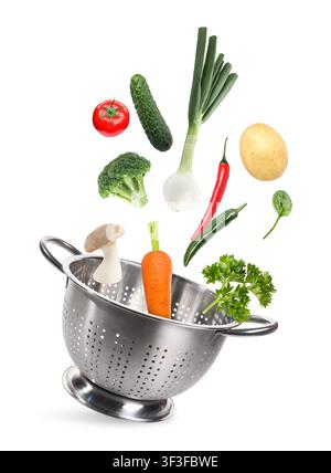 Fresh vegetables and colander flying in air on white background Stock Photo