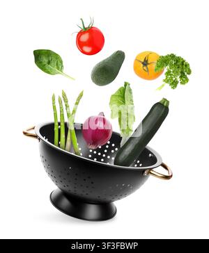 Vegetables and colander flying in air on white background Stock Photo