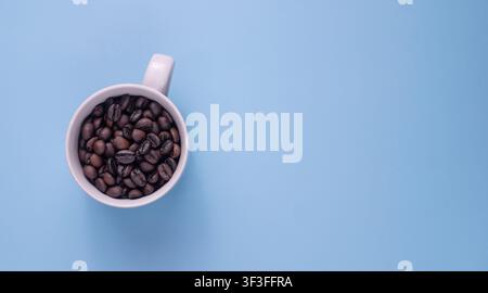 Coffee Beans in White Mug on Blue Background wit Copy Space Stock Photo