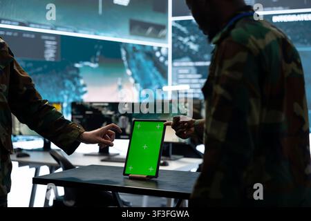 Close up of green screen mockup tablet used by army officers to look at aerial surveillance imagery. Military specialists analyze target data and intelligence feed on chroma key devices displays Stock Photo