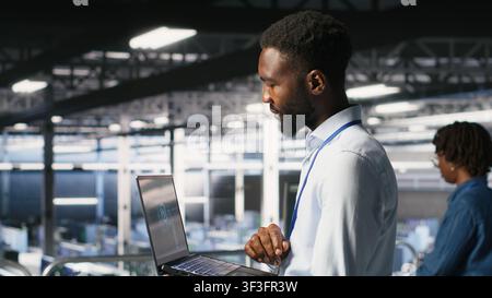 Server hub teamworking IT experts visualizing large language model architecture using notebook. Data center system administrators on industrial platform collaborating on tasks using laptop Stock Photo