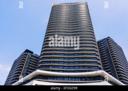 A striking view of contemporary high rise residential towers featuring distinctive curved balconies and extensive glass facades, set against a clear b Stock Photo