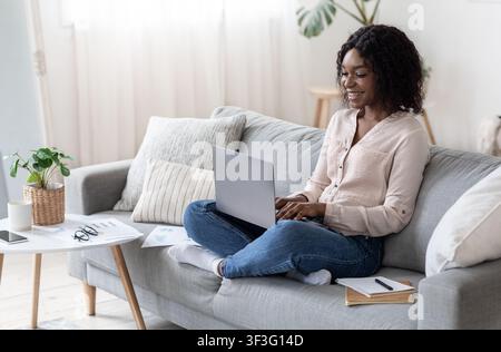 Joyful Black Freelancer Woman Working With Laptop Computer At Home Stock Photo