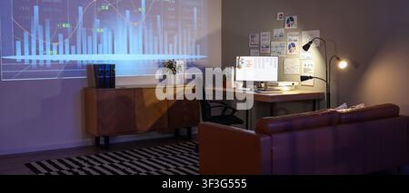 Home office interior with financial data projection on wall and computer monitor displaying charts, a computer monitor on a wooden desk also shows dat Stock Photo