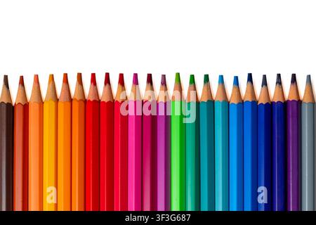 Row of vibrant colored pencils aligned horizontally at the bottom edge against a pure white background. Creativity, education, and art concept. Stock Photo