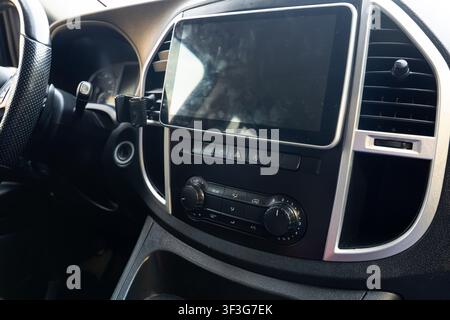 Modern car dashboard with central touchscreen, climate control knobs, air vents, and steering wheel, showcasing automotive technology, comfort Stock Photo