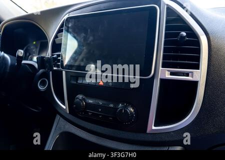 Modern car dashboard with central touchscreen, climate control knobs, air vents, and steering wheel, showcasing automotive technology, comfort Stock Photo