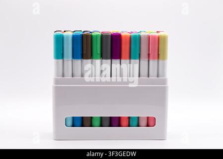 A large set of multicolored felt tip markers arranged in a white plastic container isolated on a white background. Stock Photo