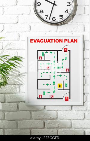 Emergency evacuation plan displayed on wall with clock showing time Stock Photo