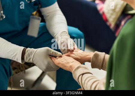 Doctor Holding Senior Womans Hands during Home Care Visit Stock Photo