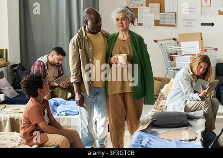 Senior Woman and Black Man Waiting in Emergency Shelter Center Stock Photo