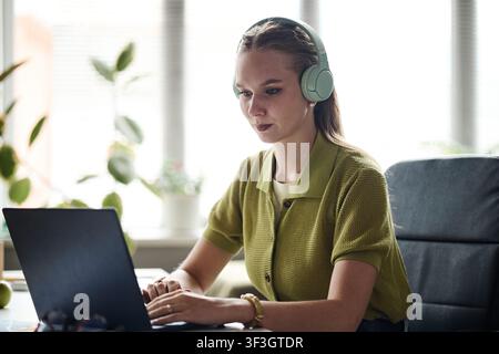 Adult Woman Wearing Headphones Working on Laptop from Home Stock Photo