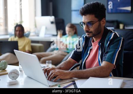 Adult Indian Man Working on Laptop in Shared Office Workspace Stock Photo