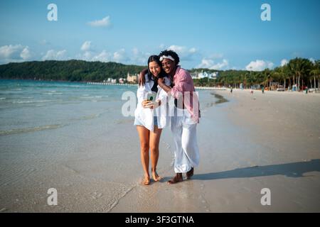 Trendy digital creator couple taking selfie by the beach, sharing travel content for social media Stock Photo