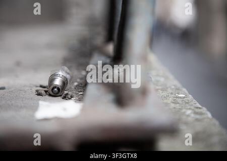 broken light bulb lying on concrete ground in urban decay setting with debris and metal bars, neglected and abandoned atmosphere, industrial and Stock Photo