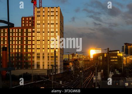 Apartment towers catching golden light beside railway tracks converging toward Leeds skyline Stock Photo