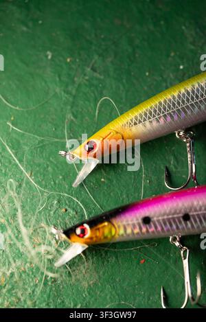 Comparison of two different colored fishing baits lying on a green boat deck surrounded by fishing line Stock Photo
