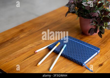Blue notebook with colored pencils arranged on a wooden table, education and creativity concept. Stock Photo