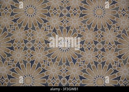 Intricate traditional Islamic geometric mosaic pattern featuring interlocking star and polygon motifs crafted from beige, gold, and blue marble tiles Stock Photo