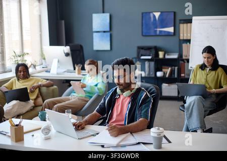 Diverse Coworkers Working on Laptops in Collaborative Office Stock Photo