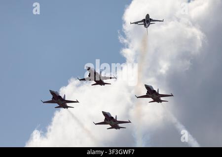 Formation of military jet aircraft flying through the sky during an aerial demonstration with dramatic clouds in the background. Stock Photo