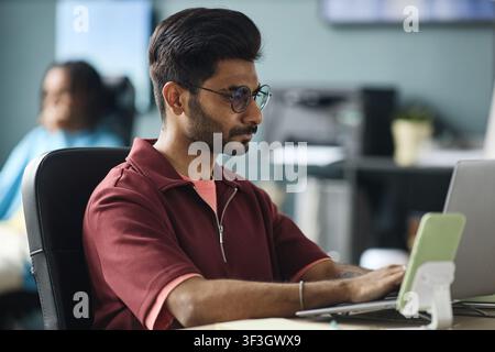 Adult Indian Man Working on Laptop in Modern Office Stock Photo