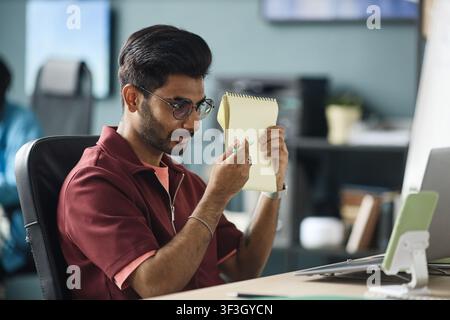 Adult Indian Man Reviewing Notes While Working in Office Stock Photo