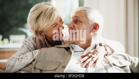 Hug, smile and couple on sofa in home for bonding, love and connection in marriage on weekend. Happy, care and mature woman embracing man in living Stock Photo