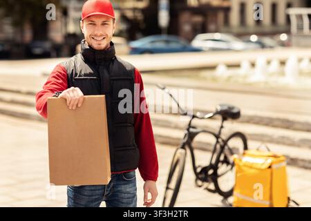 Courier Guy Holding Package Smiling To Camera Standing Outside Stock Photo