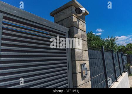 Video surveillance camera installed above the entrance gate to a luxury villa by the sea, security camera, fine for recording video and audio in a pub Stock Photo