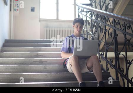 Young student working on a laptop on a staircase Stock Photo