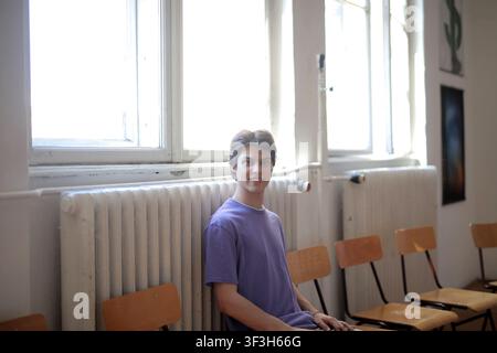 Young male student sitting in a sunlit classroom Stock Photo