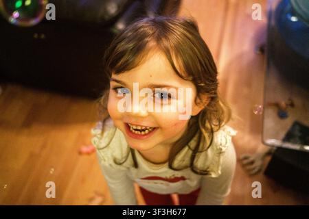 Close-up view of a smiling child playing with soap bubbles in a living room during Christmas Eve in a family home in Saint-Jacut-de-la-Mer, Cotes-d Ar Stock Photo