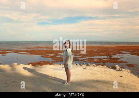 Young woman standing on a beach during golden hour Stock Photo